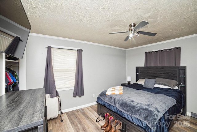 bedroom featuring ceiling fan, wood finished floors, and crown molding