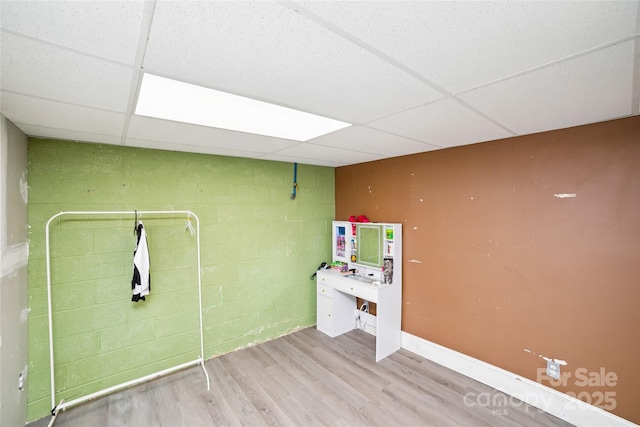 clothes washing area featuring concrete block wall and wood finished floors