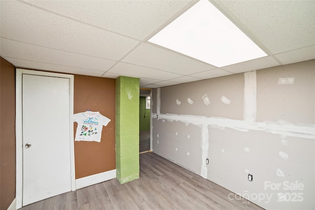 finished below grade area with a paneled ceiling, baseboards, and wood finished floors