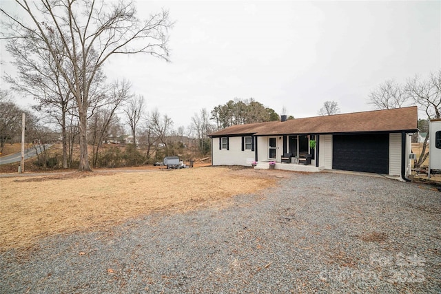 view of front of property featuring gravel driveway and a garage