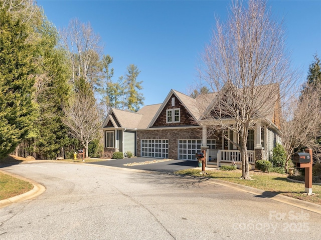 view of front of house with stone siding, aphalt driveway, a porch, and an attached garage