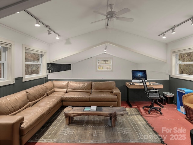 living area with a ceiling fan, lofted ceiling, and a wainscoted wall