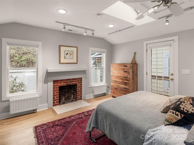 bedroom featuring multiple windows, lofted ceiling with skylight, and radiator heating unit