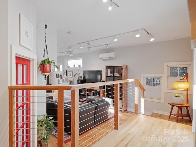 living area with wood finished floors, ceiling fan, and a wall mounted AC