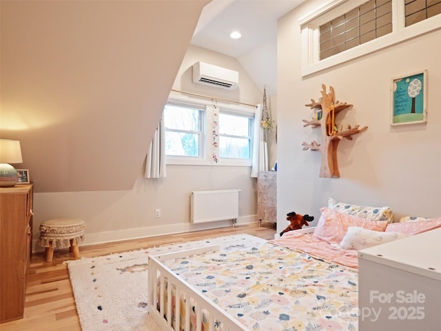 bedroom featuring baseboards, vaulted ceiling, a wall mounted AC, light wood finished floors, and radiator heating unit