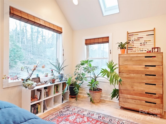 sitting room with vaulted ceiling with skylight and wood finished floors