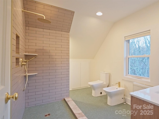 bathroom featuring lofted ceiling, toilet, a bidet, vanity, and tiled shower