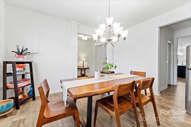 dining room featuring light wood-type flooring, baseboards, and a notable chandelier