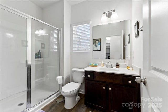 bathroom featuring a stall shower, vanity, toilet, and wood finished floors