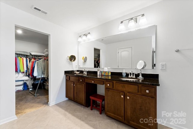 full bath with a walk in closet, double vanity, visible vents, a sink, and tile patterned floors