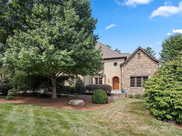 view of front facade with stone siding and a front lawn