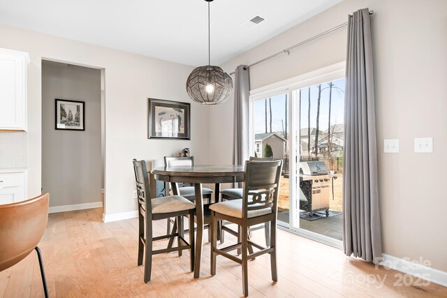 dining area featuring light wood-style flooring, visible vents, and baseboards