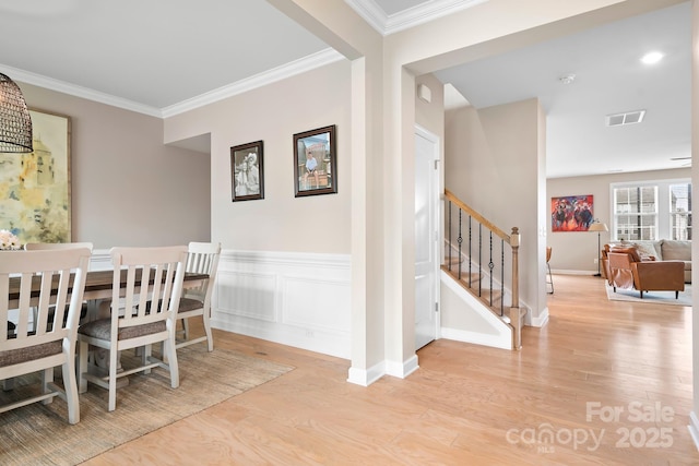 dining room featuring crown molding, stairway, wood finished floors, and wainscoting