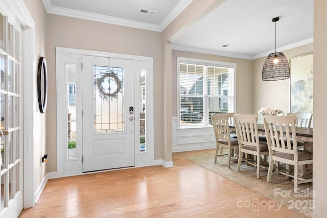 entryway with ornamental molding, light wood-type flooring, and visible vents