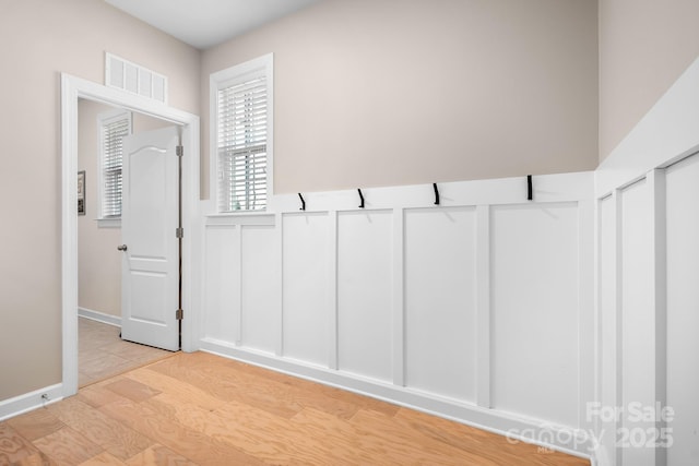 interior space featuring a wainscoted wall, light wood-style flooring, and a decorative wall