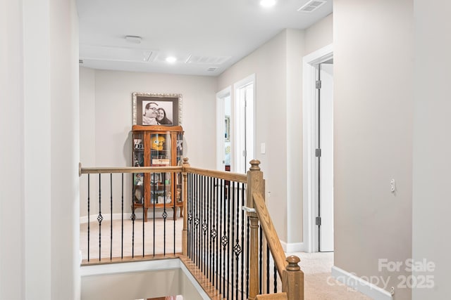 corridor with visible vents, carpet flooring, an upstairs landing, and baseboards