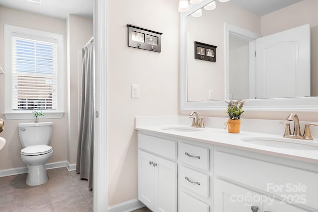 full bath featuring toilet, double vanity, a sink, and tile patterned floors