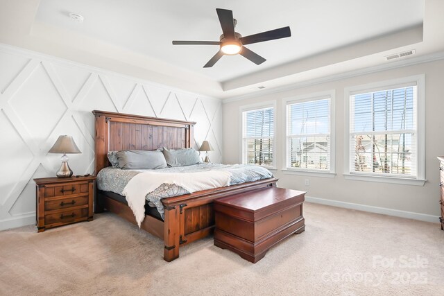 bedroom with a raised ceiling, light carpet, and multiple windows