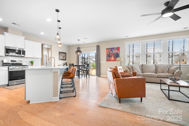 living room with recessed lighting, visible vents, baseboards, a ceiling fan, and light wood-type flooring