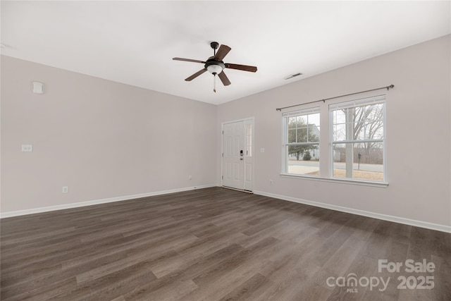 unfurnished room featuring baseboards, visible vents, dark wood finished floors, and a ceiling fan