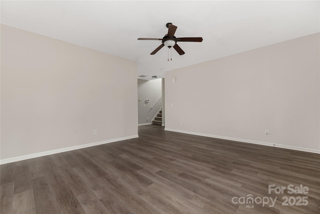 spare room with dark wood-style floors, stairway, baseboards, and a ceiling fan