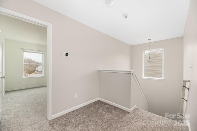 hallway with baseboards, carpet flooring, and an upstairs landing