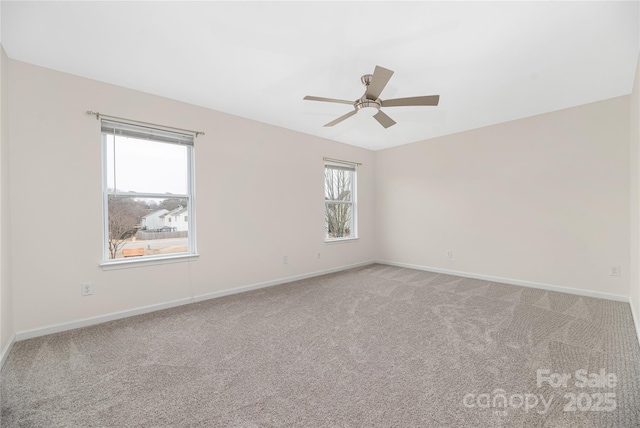 spare room featuring light carpet, ceiling fan, and baseboards