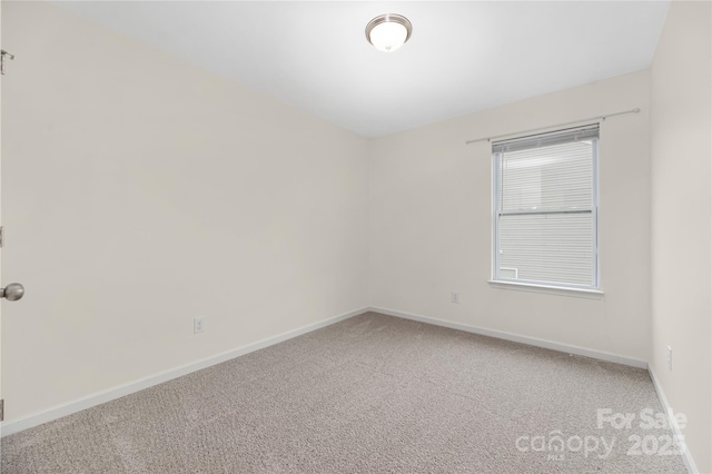 carpeted empty room featuring baseboards