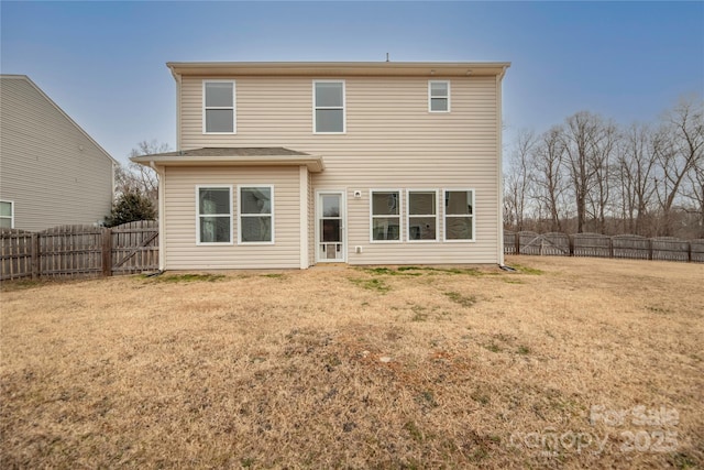 back of house with a fenced backyard and a lawn