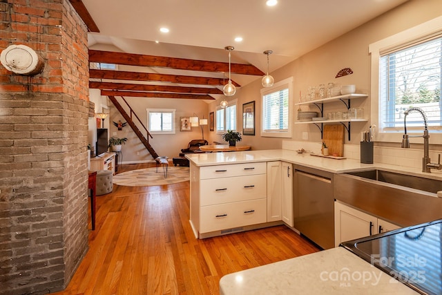 kitchen with stainless steel dishwasher, white cabinets, a sink, plenty of natural light, and a peninsula