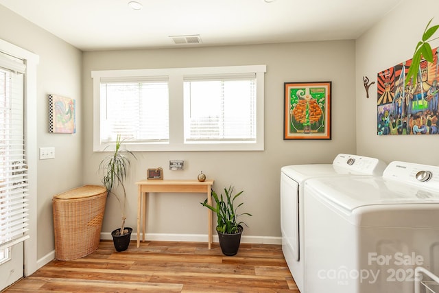 washroom with laundry area, baseboards, visible vents, wood finished floors, and washer and dryer