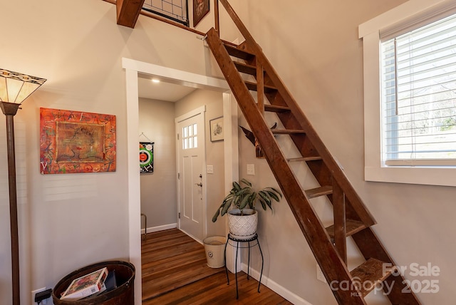 stairs with plenty of natural light, baseboards, and wood finished floors