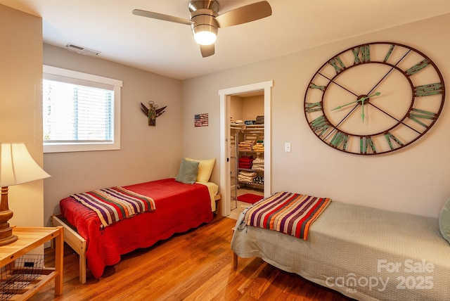 bedroom featuring a ceiling fan, visible vents, and wood finished floors