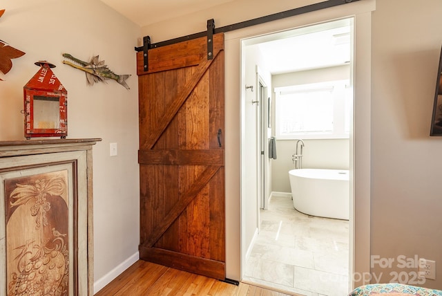 bathroom featuring a freestanding bath, wood finished floors, and baseboards