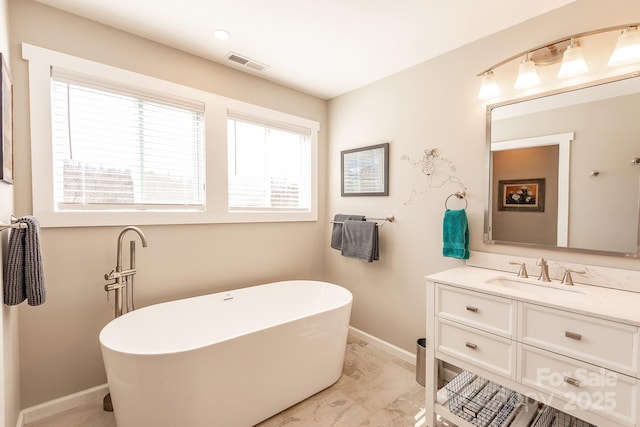 bathroom featuring marble finish floor, visible vents, vanity, a freestanding tub, and baseboards