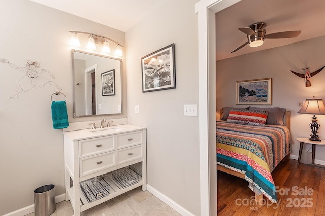 bedroom with baseboards, a sink, and wood finished floors