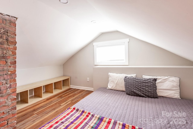 bedroom with lofted ceiling and wood finished floors