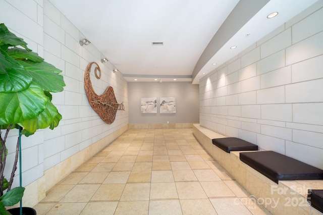 hallway featuring light tile patterned floors, visible vents, tile walls, and recessed lighting