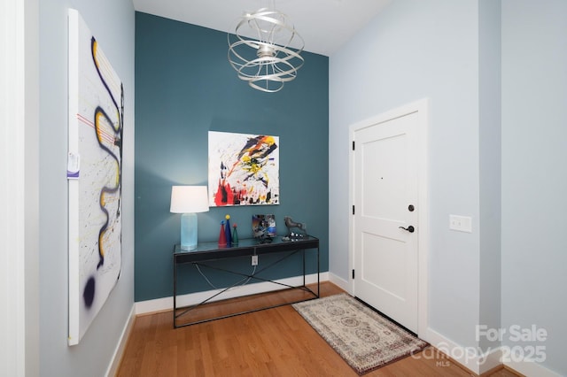 entrance foyer featuring a notable chandelier, baseboards, and wood finished floors