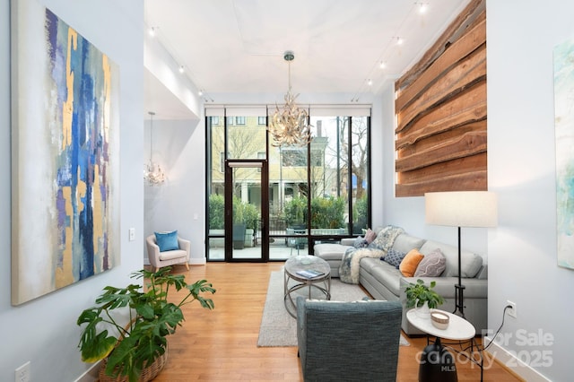 living area featuring light wood-type flooring, baseboards, an inviting chandelier, and floor to ceiling windows