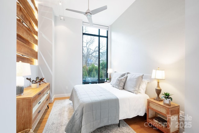 bedroom with light wood-type flooring, baseboards, and floor to ceiling windows