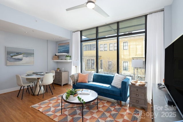 living area featuring floor to ceiling windows, wood finished floors, baseboards, and ceiling fan