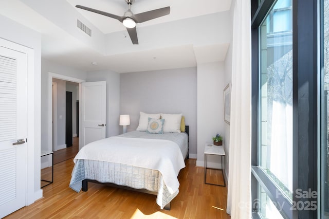 bedroom featuring ceiling fan, visible vents, baseboards, and light wood-style flooring