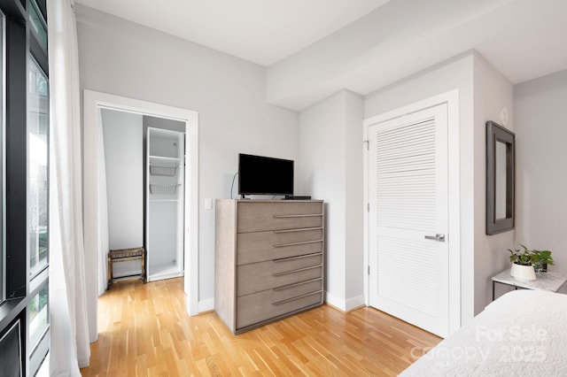 bedroom featuring a closet, light wood-type flooring, and baseboards