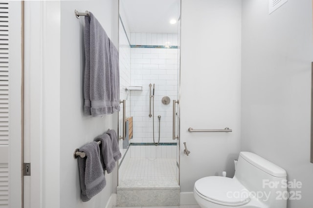 bathroom with a shower stall, toilet, and baseboards