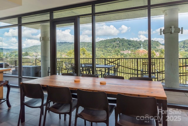 dining space featuring tile patterned floors, floor to ceiling windows, and a wooded view