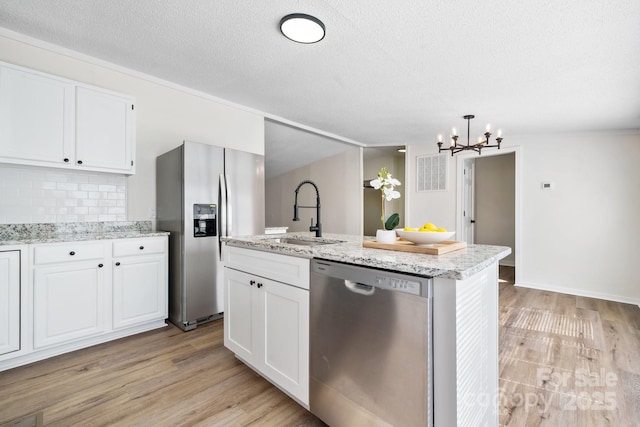 kitchen featuring appliances with stainless steel finishes, light wood-style floors, white cabinets, and a sink