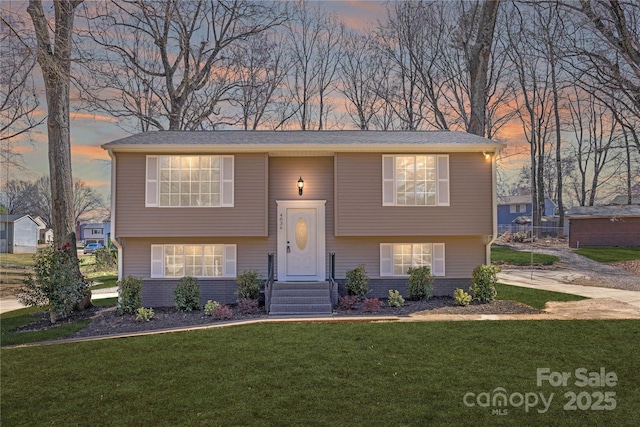 split foyer home featuring brick siding and a lawn