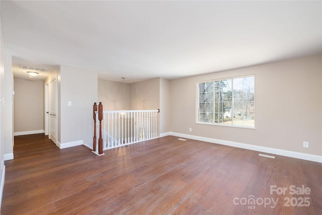 unfurnished room featuring visible vents, baseboards, and wood finished floors