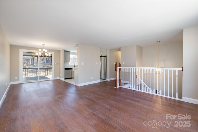 unfurnished room featuring baseboards, dark wood-style flooring, and a notable chandelier